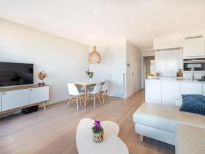 ein Wohnzimmer und eine Küche mit einem Sofa und einem Tisch in der Unterkunft Winoc 302 luxury family apartment on the dike in Koksijde