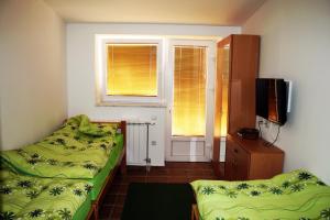 a bedroom with two beds and a tv and two windows at Hostel Mak in Sarajevo