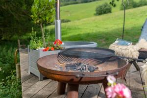 a grill on a wooden deck with a table at Tilbury Shepherd Huts with Hot Tubs Plus Holiday Cottages in West Bagborough