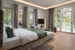 a bedroom with a large bed and large windows at SCHLOSSRESIDENZ - Boutique Apartments & Hotel Suiten in Schloß Ricklingen