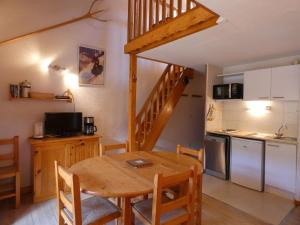 a kitchen and dining room with a wooden table and a kitchen and stairs at Appartement centre village, 6 personnes, 1 mezzanine - VLII70 in Beaufort