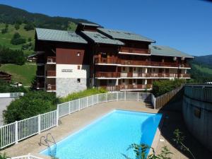 a hotel with a swimming pool in front of a building at Appartement centre village, 6 personnes, 2 chambres - VLII71 in Beaufort