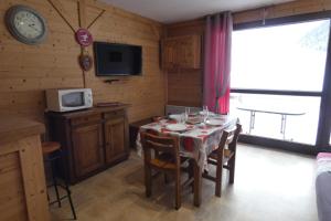 a dining room with a table with chairs and a clock at Appartement cosy, 4 personnes, 1 coin montagne - AR2005 in Beaufort