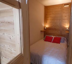a small bedroom with a bed with two red pillows at Appartement cosy, 4 personnes, 1 coin montagne - AR2005 in Beaufort
