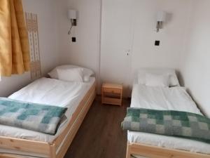2 Betten in einem Zimmer mit weißen Wänden in der Unterkunft Parti Sétány Vendégház in Balatonkenese