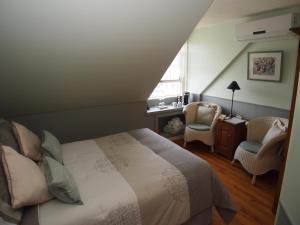 1 dormitorio con 1 cama, 1 silla y 1 ventana en Au Manoir de la rue Merry, en Magog-Orford