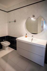 een badkamer met een wastafel, een toilet en een spiegel bij Apartamento com vista castelo in Setúbal