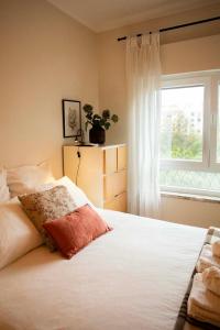 een slaapkamer met een groot wit bed en een raam bij Apartamento com vista castelo in Setúbal