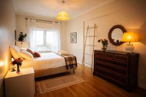 een slaapkamer met een bed, een dressoir en een spiegel bij Apartamento com vista castelo in Setúbal