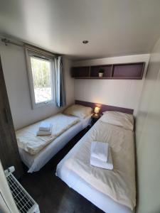 2 camas en una habitación pequeña con ventana en Ferienpark Auf dem Simpel - Mobilheim 3, en Soltau