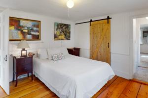 um quarto com uma cama branca e piso em madeira em Country Cottage em Indian Point