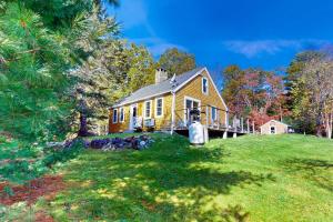 uma grande casa amarela numa colina relvada em Country Cottage em Indian Point