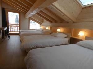 a row of beds in a room with wooden ceilings at Chalet cosy près des pistes, 12 personnes, 4 chambres - CH41 in Beaufort