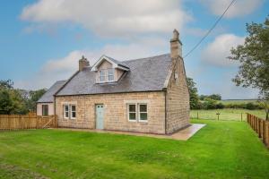 a small brick house with a green yard at Coldwells Farmhouse in Dalkeith