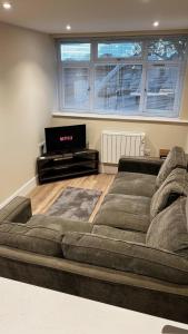 a large couch in a living room with a flat screen tv at Abbey House in Horsham
