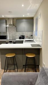a kitchen with two bar stools and a counter top at Abbey House in Horsham