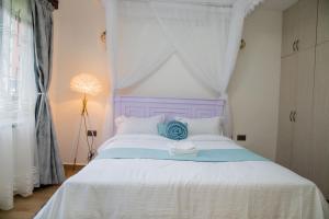 a white bed with a purple headboard in a bedroom at Sana Home by Edmor Suites in Nairobi