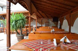 un comedor con mesas de madera y bancos en un restaurante en Hotel Eos en Kiten