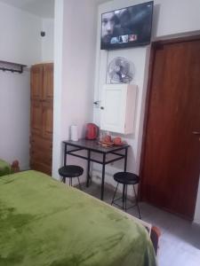 Schlafzimmer mit einem Bett, einem Tisch und einem TV in der Unterkunft Hostal Tía Dora in San Salvador de Jujuy