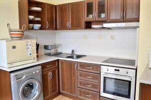 a kitchen with wooden cabinets and a washer and dryer at The Terrace Apartment in Stara Zagora