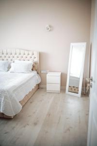 a white bedroom with a bed and a mirror at Apartament Ploiesti Central in Ploieşti