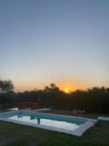 a swimming pool with the sunset in the background at Luna de los Molles in Villa Las Rosas