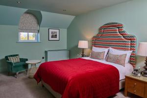 a bedroom with a large bed with a red blanket at Hotel du Vin Cheltenham in Cheltenham