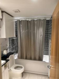 bagno con tenda per la doccia e servizi igienici di Specious apartment In Canning Town ( London ) a Londra