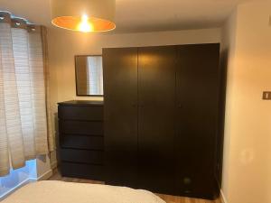 a bedroom with a black cabinet and a bed at Specious apartment In Canning Town ( London ) in London