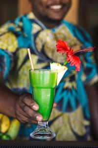 a man holding a green drink with a red flower in it at Zanzibar Queen Hotel in Matemwe