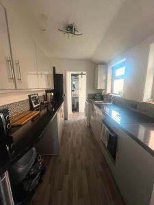 a kitchen with white cabinets and a wooden floor at Contractors,Family Large 3 Bed, 2 Bathrooms in Ilkeston