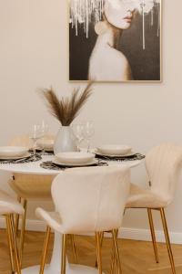 tavolo da pranzo con sedie bianche e un quadro di Bright & Elegant Apartment Warsaw by Renters a Varsavia