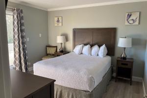 Habitación de hotel con cama con sábanas y almohadas blancas en Marco Island Lakeside Inn, en Marco Island