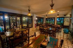 a restaurant with tables and chairs and people sitting at tables at Odoiá Maragogi Restaurante e Estalagem in Maragogi