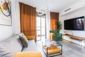 ein Wohnzimmer mit einem Sofa und einem TV in der Unterkunft 3Bedroom Suite with balcony Yona Hotel in Tel Aviv