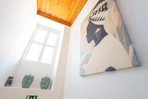 ein Gemälde an einer Wand neben einem Fenster und Vasen in der Unterkunft Eira das Lages in Seia