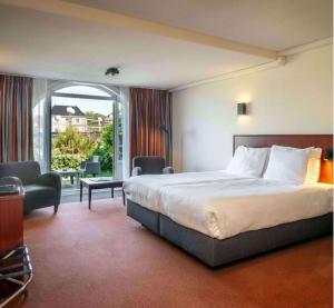 ein Hotelzimmer mit einem Bett und einem Balkon in der Unterkunft Hotel Greenside Texel in De Koog
