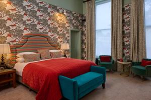 a bedroom with a bed with a red blanket and chairs at Hotel du Vin Cheltenham in Cheltenham