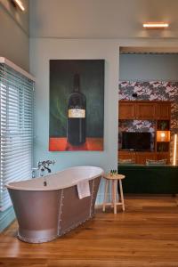 a bath tub in a bathroom with a painting of a bottle of wine at Hotel du Vin Cheltenham in Cheltenham