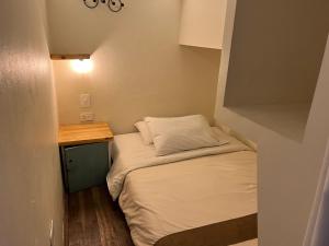 uma pequena cama num pequeno quarto com uma mesa em The Cranky Croc Hostel em Bogotá