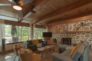 The Phoenix - riverside chalet with beach في مونت تريمبلانت: غرفة معيشة مع أرائك وجدار حجري