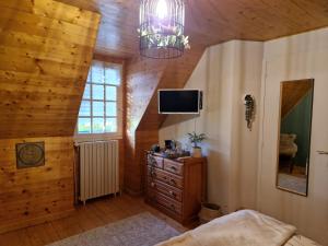 Schlafzimmer mit einem Bett und einem TV an einer Holzdecke in der Unterkunft L'Etang de la Gourdinière in Landisacq