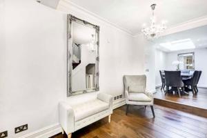 a living room with a mirror and a chair at Stunning Knightsbridge Townhouse With Patio in London