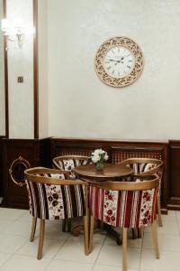 une table et des chaises avec une horloge sur un mur dans l'établissement Hotel Capitol, à Iaşi
