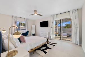 a white bedroom with a bed and a tv at Rather Be Designer Casa by Rather Be Properties in Desert Hot Springs
