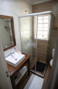 a bathroom with a sink and a shower with a glass door at Hotel Pousada do Conde in Canela