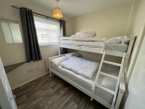 a room with two bunk beds and a window at Chalet 192, Hemsby - Two bed chalet, sleeps 5, pet friendly, bed linen and towels included in Hemsby