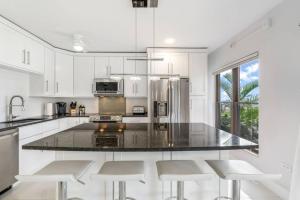 a kitchen with white cabinets and a large island with stools at George Town Villas #117 in George Town