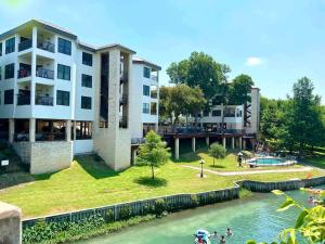 a building next to a river with people in it at Riverfront condo downtown newbraunfels in New Braunfels
