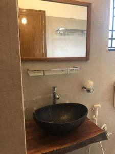uma casa de banho com um lavatório preto e um espelho em Elim-A Sedate Nest em Santiniketan